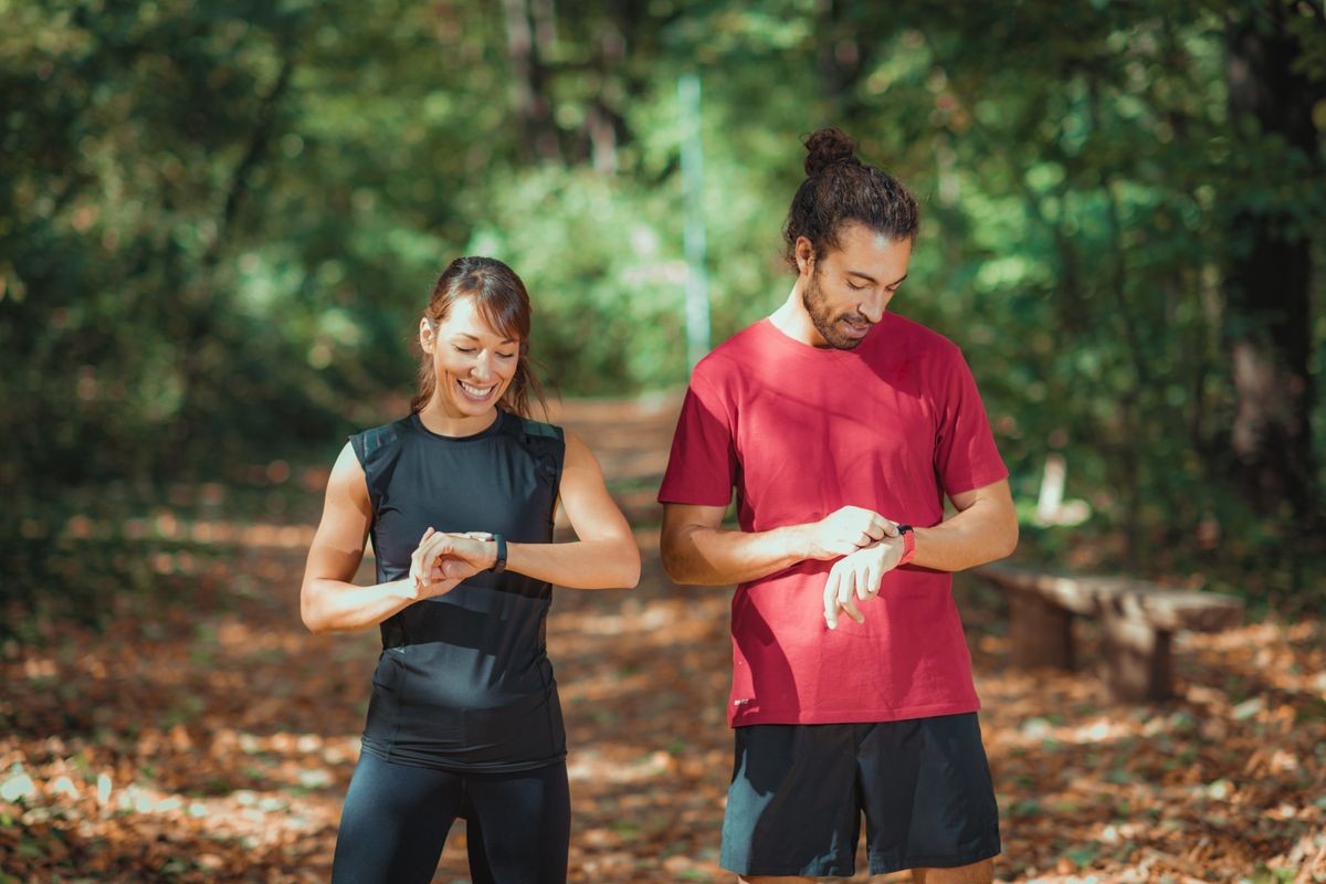 Young couple checking progress on their smart watches after outdoor training
